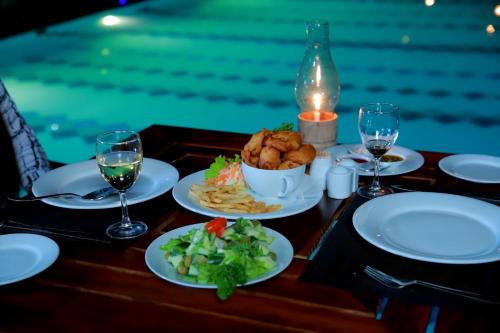 a table with plates of food and glasses of wine at Hill View Resort in Nakandalagoda
