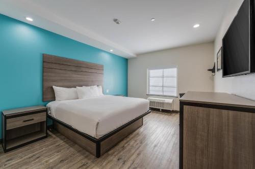 a bedroom with a bed and a blue wall at Americas Best Value Inn & Suites Katy in Katy