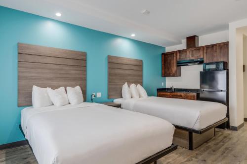 2 łóżka w pokoju hotelowym z niebieskimi ścianami w obiekcie Americas Best Value Inn & Suites Katy w mieście Katy