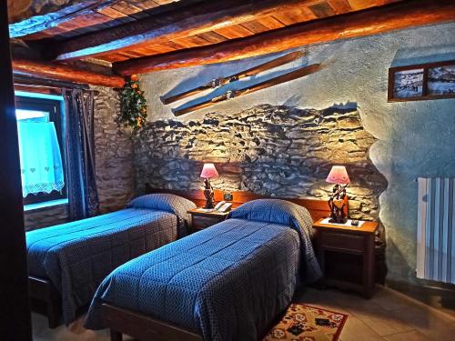 duas camas num quarto com uma parede de pedra em Etoile des Neiges em Sauze dʼOulx