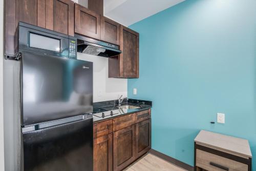 a kitchen with a black refrigerator and wooden cabinets at Red Lion Inn & Suites Katy in Katy
