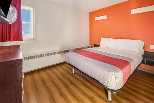 a bedroom with a bed with an orange wall at Motel 6-Lethbridge, AB in Lethbridge