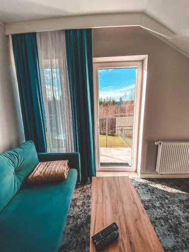 a living room with a couch and a large window at La Park Aparthotel in Kudowa-Zdrój