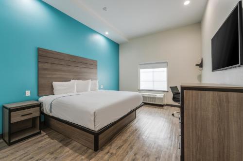 a bedroom with a bed and a flat screen tv at Red Lion Inn & Suites Katy in Katy