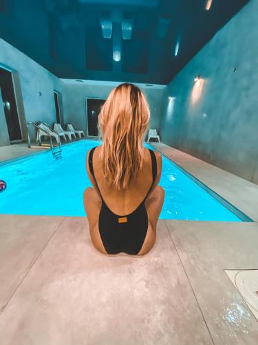 a woman sitting in front of a swimming pool at La Park Aparthotel in Kudowa-Zdrój
