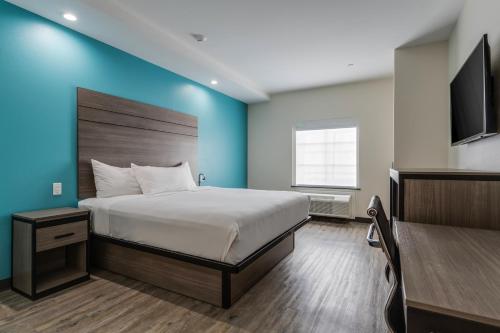 a bedroom with a large bed and a blue wall at Red Lion Inn & Suites Katy in Katy