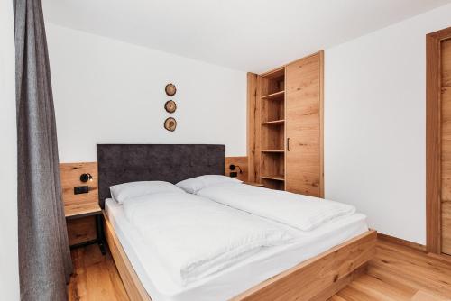 a bedroom with a white bed and a wooden cabinet at Höllerhof Brixen in Albes