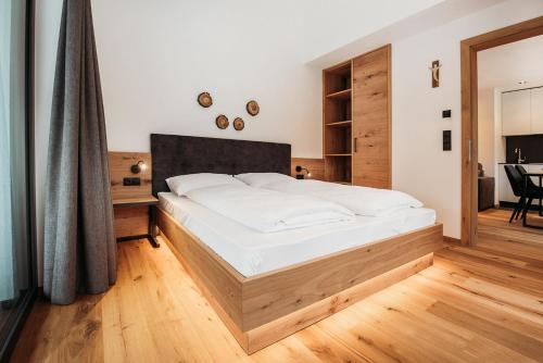a bedroom with a large white bed with a wooden headboard at Höllerhof Brixen in Albes
