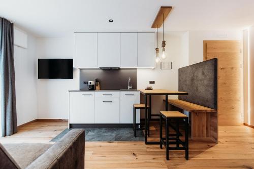 a kitchen with white cabinets and a wooden table at Höllerhof Brixen in Albes