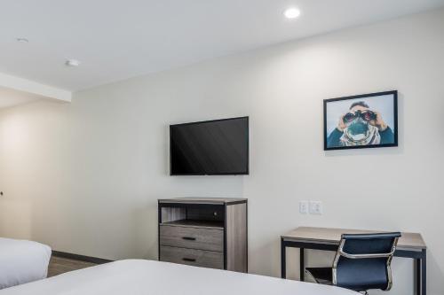 a room with a bed and a table and a tv at Red Lion Inn & Suites Katy in Katy