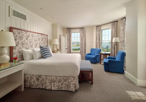 a bedroom with a bed and two blue chairs at Harbor View Hotel in Edgartown