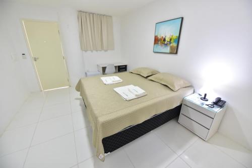 a small white room with a bed and a bathroom at LIVE IN FORTALEZA HOTEL in Fortaleza