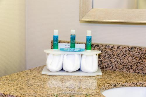 a bathroom counter with three toothbrushes and candles on it at Holiday Inn Express Hotel & Suites Grand Rapids-North by IHG in Grand Rapids