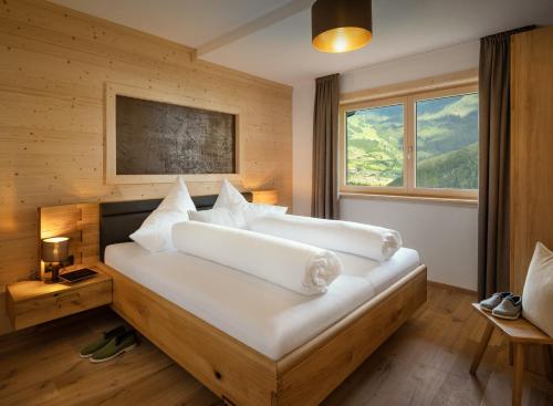 a bedroom with a large white bed with a window at Appartements Bichl ,Haus Ausblick in Wenns