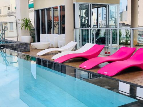 a swimming pool with pink chairs in a building at 303 - Rentaqui - Studio Augusta Elegance Pool New in Sao Paulo