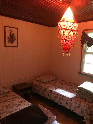 Zimmer mit 2 Betten und einem Kronleuchter in der Unterkunft Casa Colonial Santuário Bellatrix in Faxinal dos Castilhos
