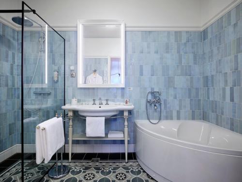 a blue tiled bathroom with a tub and a sink at Villa Ammende Restaurant and Hotel in Pärnu