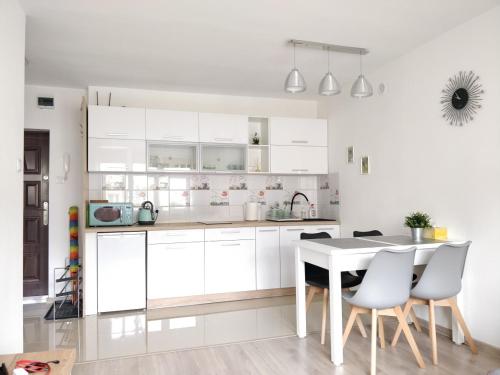 a kitchen with white cabinets and a table and chairs at Apartament Hel Leśna 8 in Hel