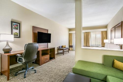 a hotel room with a green couch and a desk at Aspire Hotel and Suites in Gettysburg