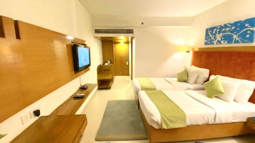 a hotel room with two beds and a flat screen tv at Gis Select Banjara Hill in Hyderabad