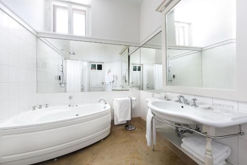 a white bathroom with a tub and a sink at Villa Ammende Restaurant and Hotel in Pärnu