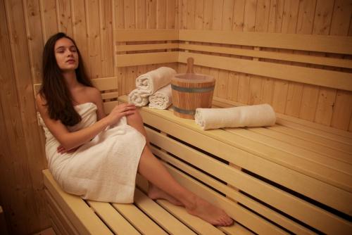 a woman is sitting in a sauna at Hotel Vila Anna in Trenčianske Teplice