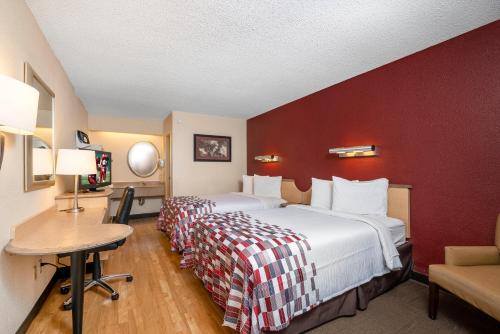 a hotel room with a large bed with a red wall at Red Roof Inn Detroit Metro Airport - Taylor in Taylor