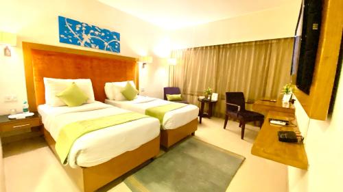 a hotel room with two beds and a desk at Gis Select Banjara Hill in Hyderabad