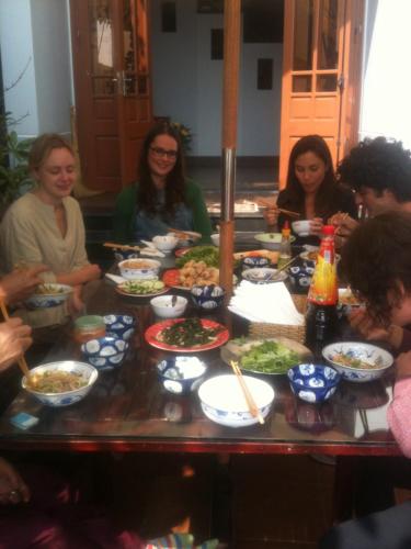 un grupo de personas sentadas alrededor de una mesa con comida en Hai Dang Homestay, en Hoi An