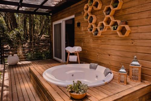 a tub on a deck with a wooden house at Vila Nambu - Exclusive Pousada in Gramado