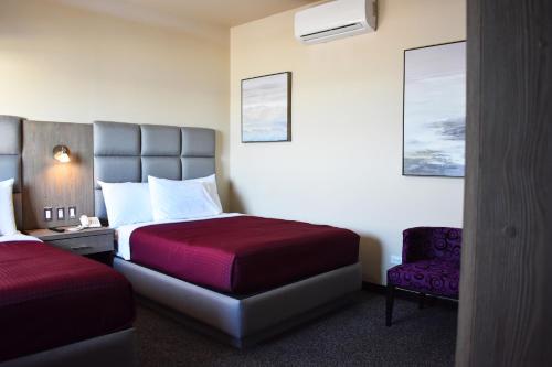 um quarto de hotel com duas camas e uma cadeira em Hotel Jatay em Tijuana