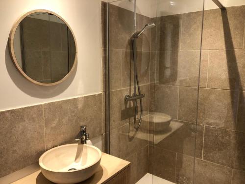 une salle de bain avec un lavabo et une douche avec un miroir dans l'établissement Les Crouquets La cabane SPA des Noyers, à Jayac
