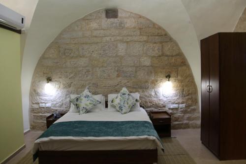 a bedroom with a bed with a stone wall at Dar Sitti Aziza in Bethlehem