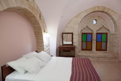 a bedroom with a white bed and a window at Dar Sitti Aziza in Bethlehem