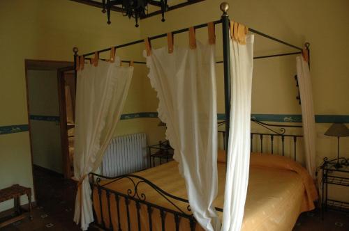 a bedroom with a canopy bed with white curtains at Hotel Arabia in Albarracín