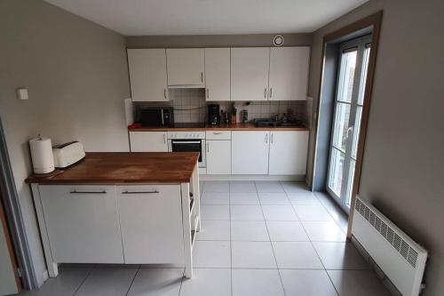 a kitchen with white cabinets and a wooden counter top at Maison au bord de lac in Ghyvelde