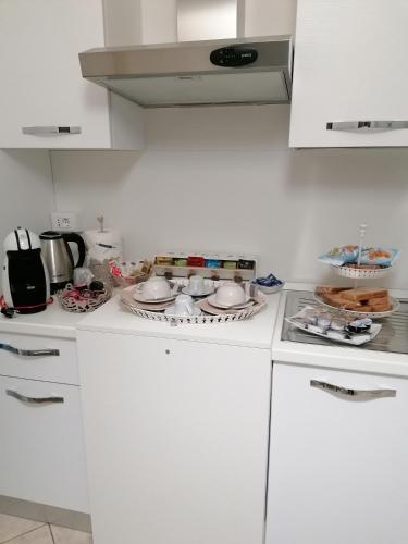 une cuisine blanche avec un plan de travail recouvert de vaisselle. dans l'établissement B&B Casa Gaia - Sirmione, à Sirmione