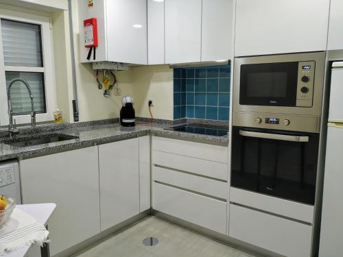 a kitchen with white cabinets and a microwave at Home Aveiro Ria in Aveiro