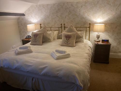 a large white bed with two towels on it at The Royal Oak Inn in Withypool