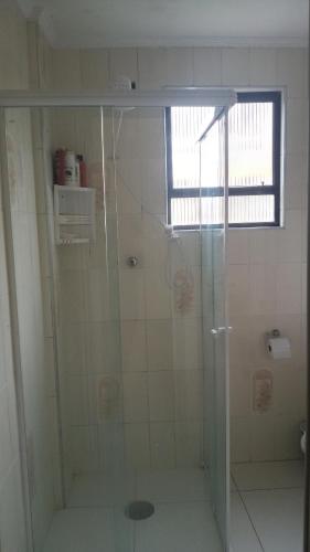 La salle de bains est pourvue d'une douche avec une porte en verre. dans l'établissement Apartamento com1 vaga na garagem FREE ! PRAIA GRANDE, à São Paulo