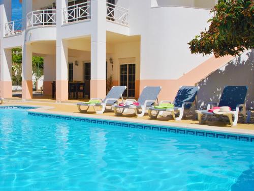 a pool with chaise lounge chairs next to a house at Villa Nespereira by Algarve Vacation in Albufeira