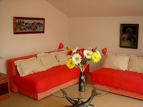 a living room with two red couches and a vase of flowers at Apartments Odalović in Bijela