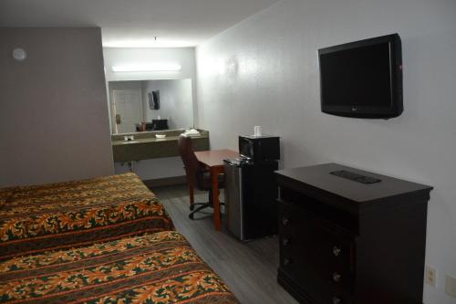 a hotel room with two beds and a flat screen tv at Deluxe Inn Irving in Irving