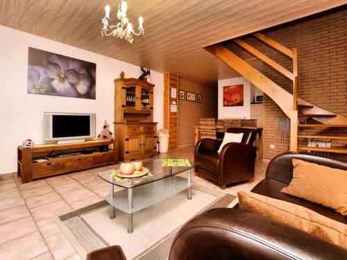 een woonkamer met een bank en een televisie bij Small simple and reasonably priced semi detached house with its own terrace in Houffalize