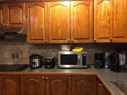 a kitchen with wooden cabinets and a microwave on a counter at Hamptons Rose garden family! in Calgary