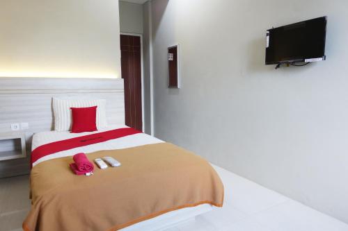 1 dormitorio con 1 cama con almohadas rojas y TV en Kelir Residence, en Kalibanteng-lor