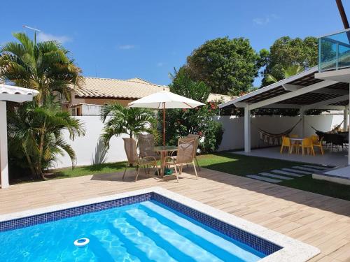 basen ze stołem, krzesłami i parasolem w obiekcie Guarajuba - casa em condomínio corais a 200 metros da praia w mieście Camaçari