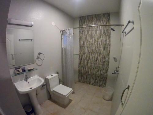 a bathroom with a toilet and a shower and a sink at BaywoodGoa in Morjim