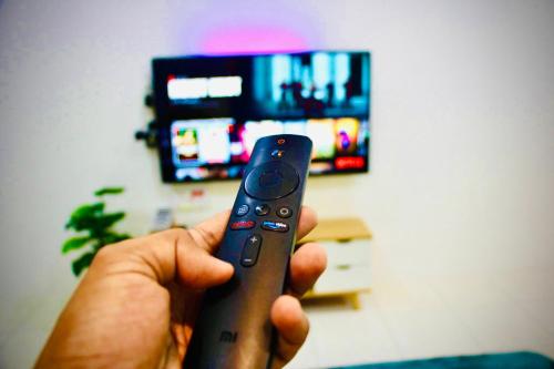 a person holding a remote control in front of a tv at Bismillah Homestay Muslem NETFLIX UNIFI HIGH SPEED in Kamunting