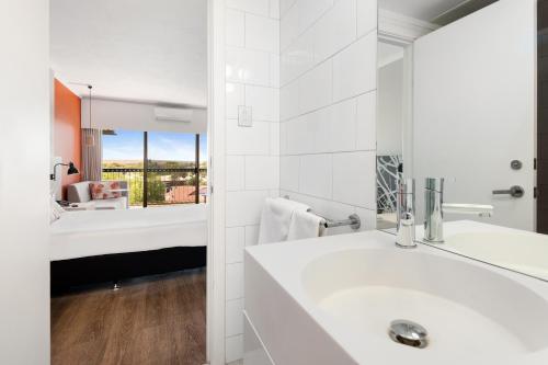 Baño blanco con lavabo y espejo en The Plaza Hotel Kalgoorlie en Kalgoorlie